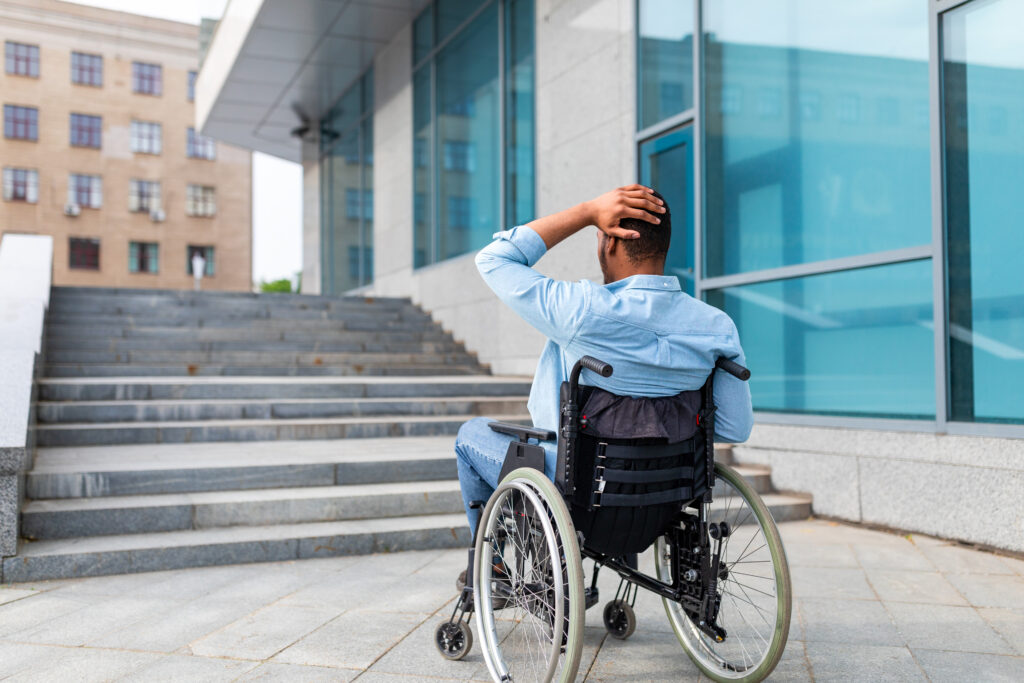 Man in wheelchair encounters outside stairs with no wheelchair ramp