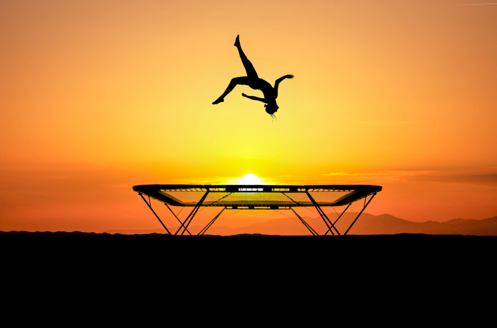 Trampoline with gymnast and sun setting behind