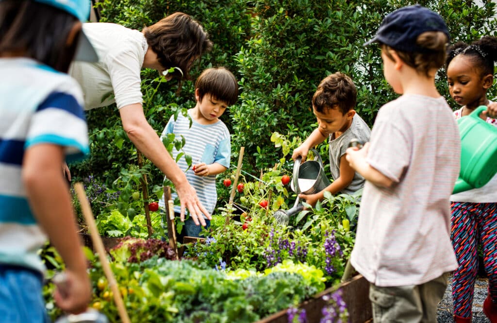 Parents and children learning about gardening and ecology outside in a garden