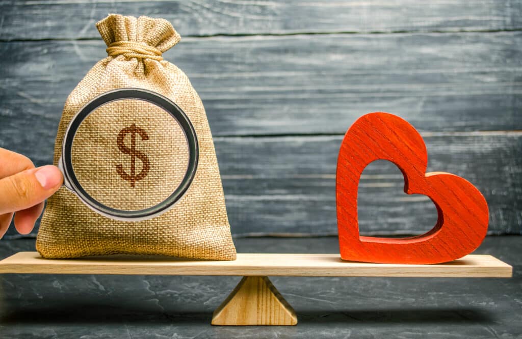 Scale balance with bag of money and a red heart - which one do you love the most?
