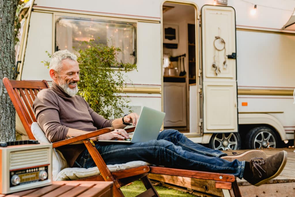 Man reading, reclined on a lounge chair, outside his RV