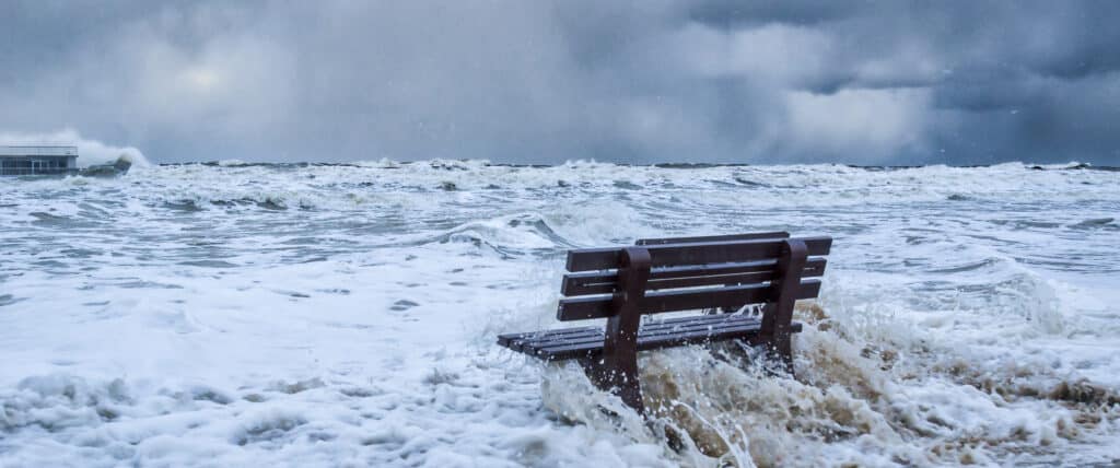 Waters rising from ocean partially flooding seaside bench