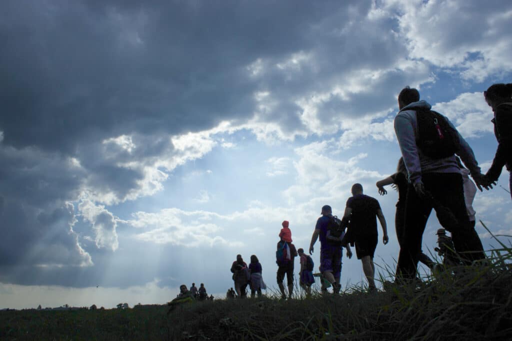 Refugees walking in a line against dusk skies