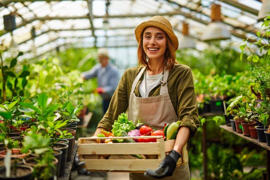 Woman in greenhouse holding a basket of vegetables